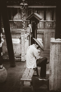 Side view of man sitting on seat in city