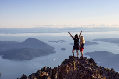 People standing on rock by mountain against sky