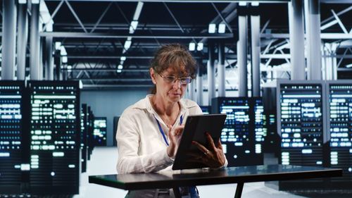 Businesswoman using laptop while standing in office
