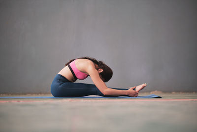 Woman with arms raised while sitting on floor