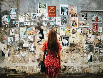 Rear view of woman standing against graffiti wall