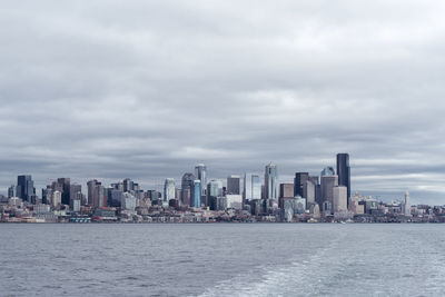 Sea by cityscape against sky