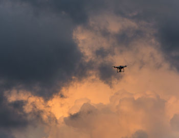 Low angle view of quad copter drone against clouds