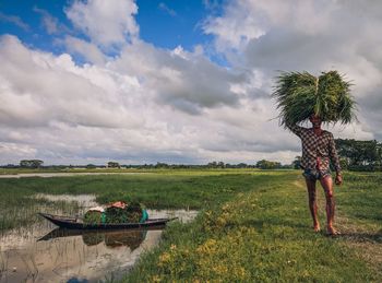 Rear view of woman standing by lake against sky