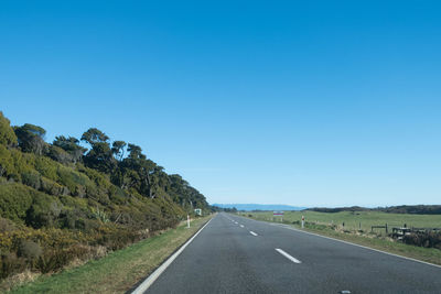 Empty road against clear blue sky