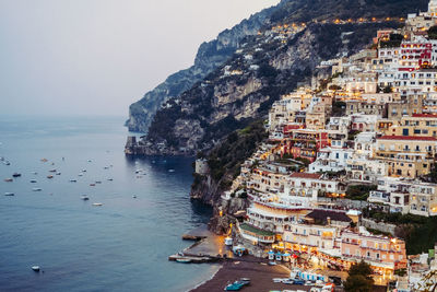 Aerial view of city by sea against sky