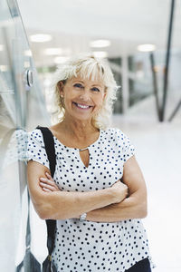 Portrait of happy businesswoman standing arms crossed in modern office