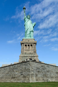 Low angle view of statue of historical building against cloudy sky