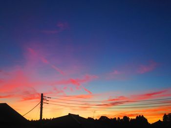 Low angle view of silhouette electricity pylon against romantic sky