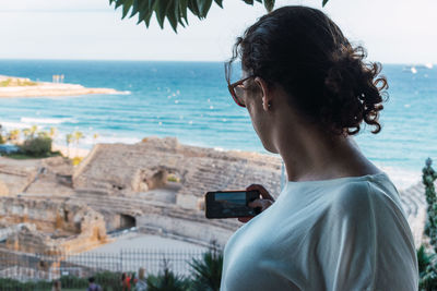 Woman from back taking a photo with the smarthphone to a monument