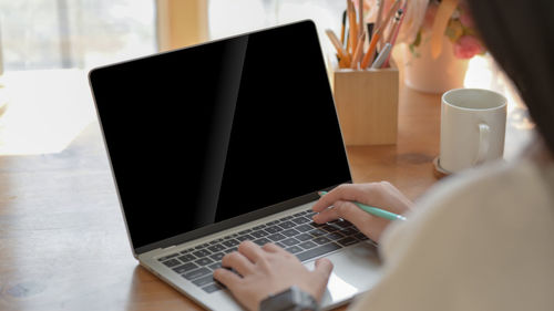 Midsection of woman using laptop on table