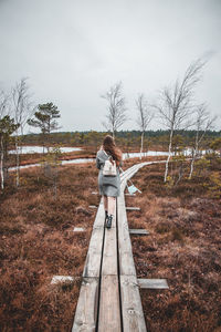 Rear view of young woman standing on land against sky