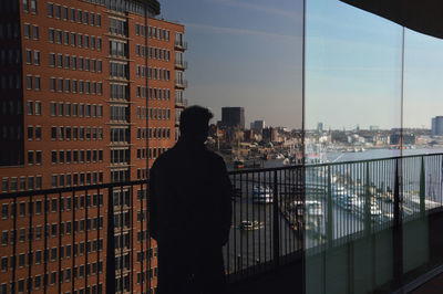 Rear view of man in city against sky