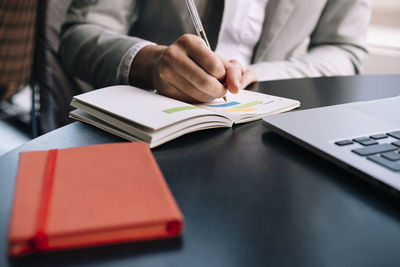 Businesswoman writing in diary with pen at table in cafe