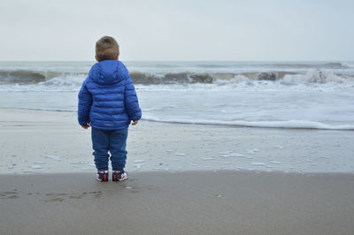 Rear view of boy standing on beach