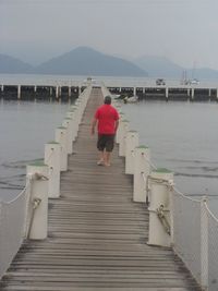 Rear view of woman walking on sea shore against clear sky