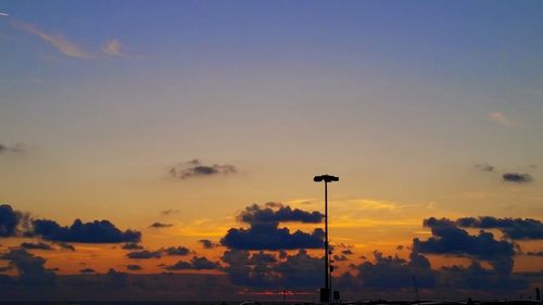 Silhouette street light against sky at sunset