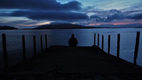 Rear view of silhouette man on pier at sunset