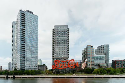 Modern buildings by river against sky in city