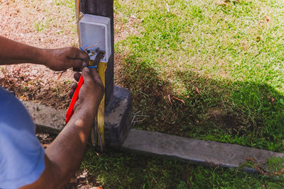 Electrician's hand stripping electrical wires with stationery knife.