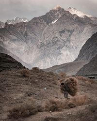 Man carrying hay against mountains during winter