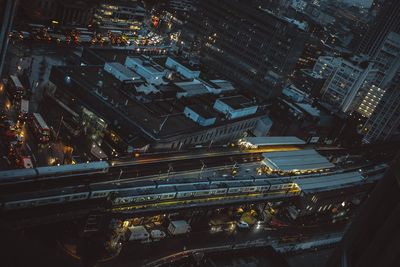 High angle view of illuminated railroad tracks amidst buildings at night
