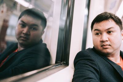 Portrait of young man sitting at window