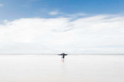 Rear view of woman swimming in sea against sky