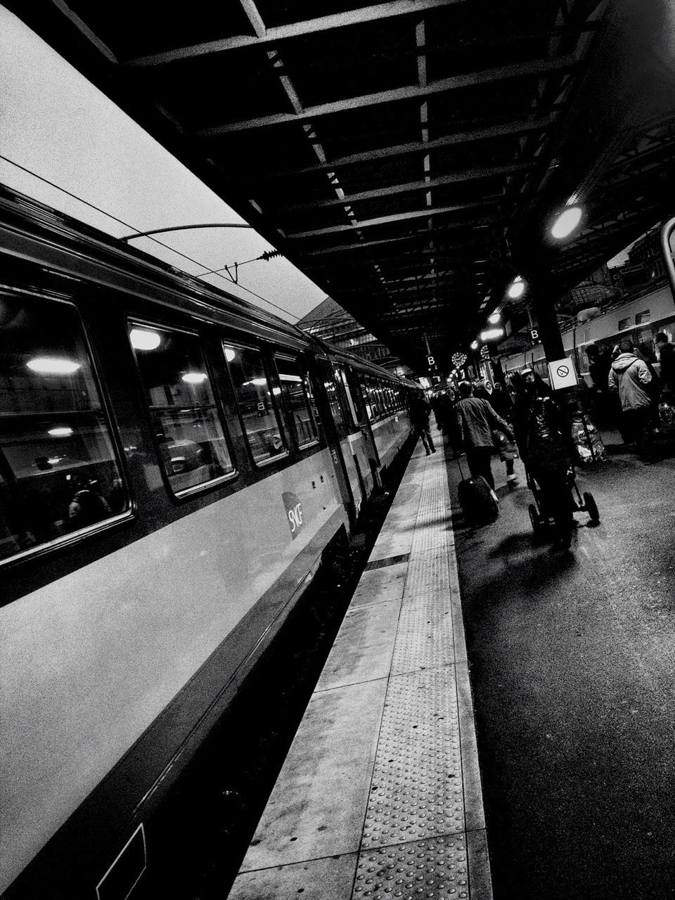 indoors, transportation, illuminated, ceiling, railroad station, railroad station platform, incidental people, public transportation, mode of transport, architecture, built structure, travel, rail transportation, lighting equipment, city life, subway station, railroad track, night, flooring