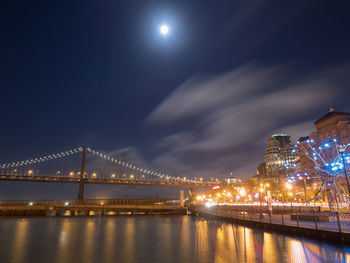 Illuminated bridge over river at night