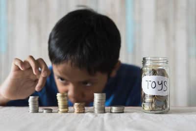 Boy putting coins in jar on table