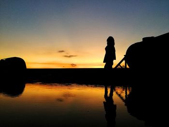 Silhouette man standing on beach against sky during sunset