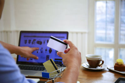 Midsection of man using smart phone on table