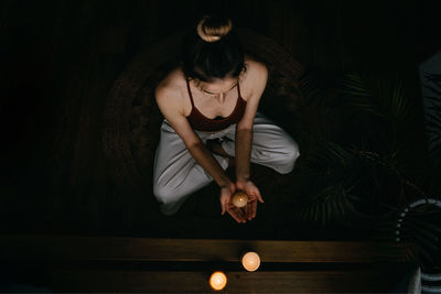 Young woman sitting against black background