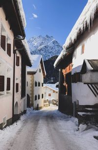 Snow covered houses by buildings against sky