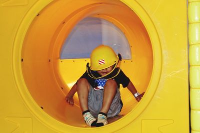 Cute boy playing in yellow tunnel slide