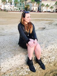 Young woman sitting on retaining wall at beach