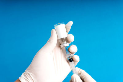 Close-up of hand holding white against blue background