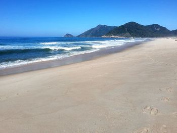 Scenic view of beach against clear blue sky