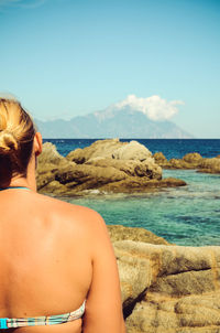 Rear view of woman at beach against sky