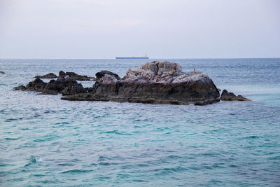 Rock formation in sea against clear sky