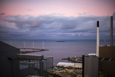 Buildings by sea against sky during sunset