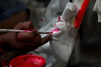 Cropped hand of person painting statue in workshop