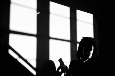 Woman standing by wall on sunny day