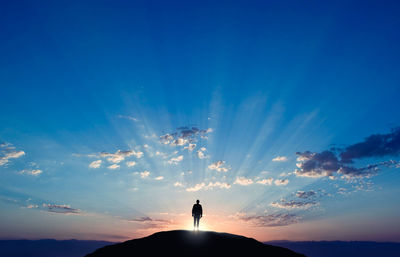 Silhouette man standing on mountain against sky during sunset