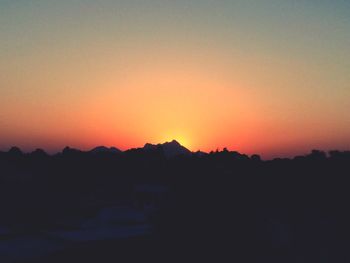 Silhouette landscape against orange sky