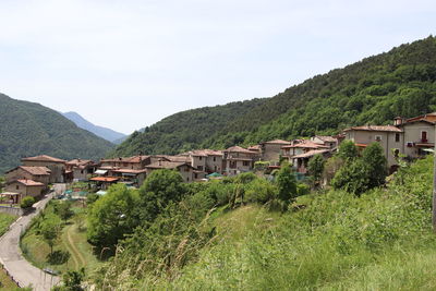 Houses amidst trees and buildings against sky