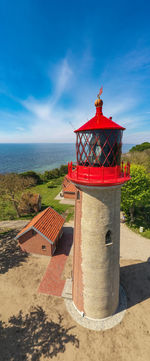 Traditional windmill on beach by sea against sky