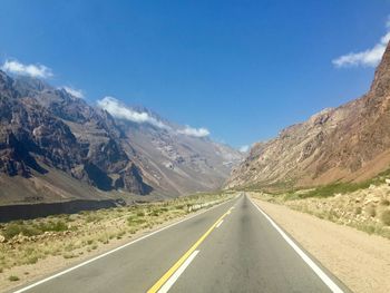 Empty road by mountains against sky