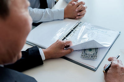 Midsection of man holding paper with text on table